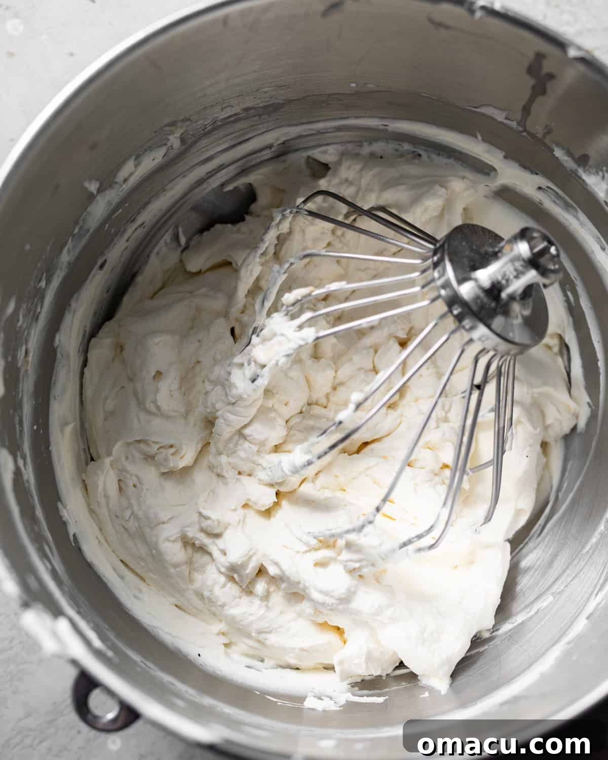 The luxurious Chantilly cream frosting, a perfect blend of mascarpone and whipped cream, sits in a mixing bowl with the whisk attachment, showcasing its stiff peaks.
