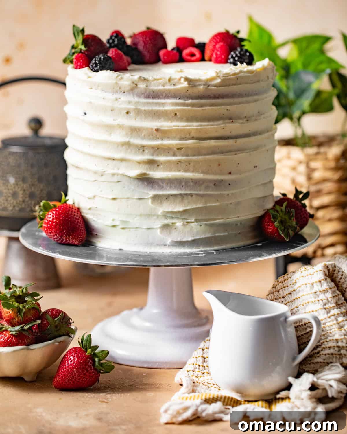 A grand Berry Chantilly Cake, beautifully frosted and generously topped with a vibrant array of fresh mixed berries, proudly displayed on a cake stand.