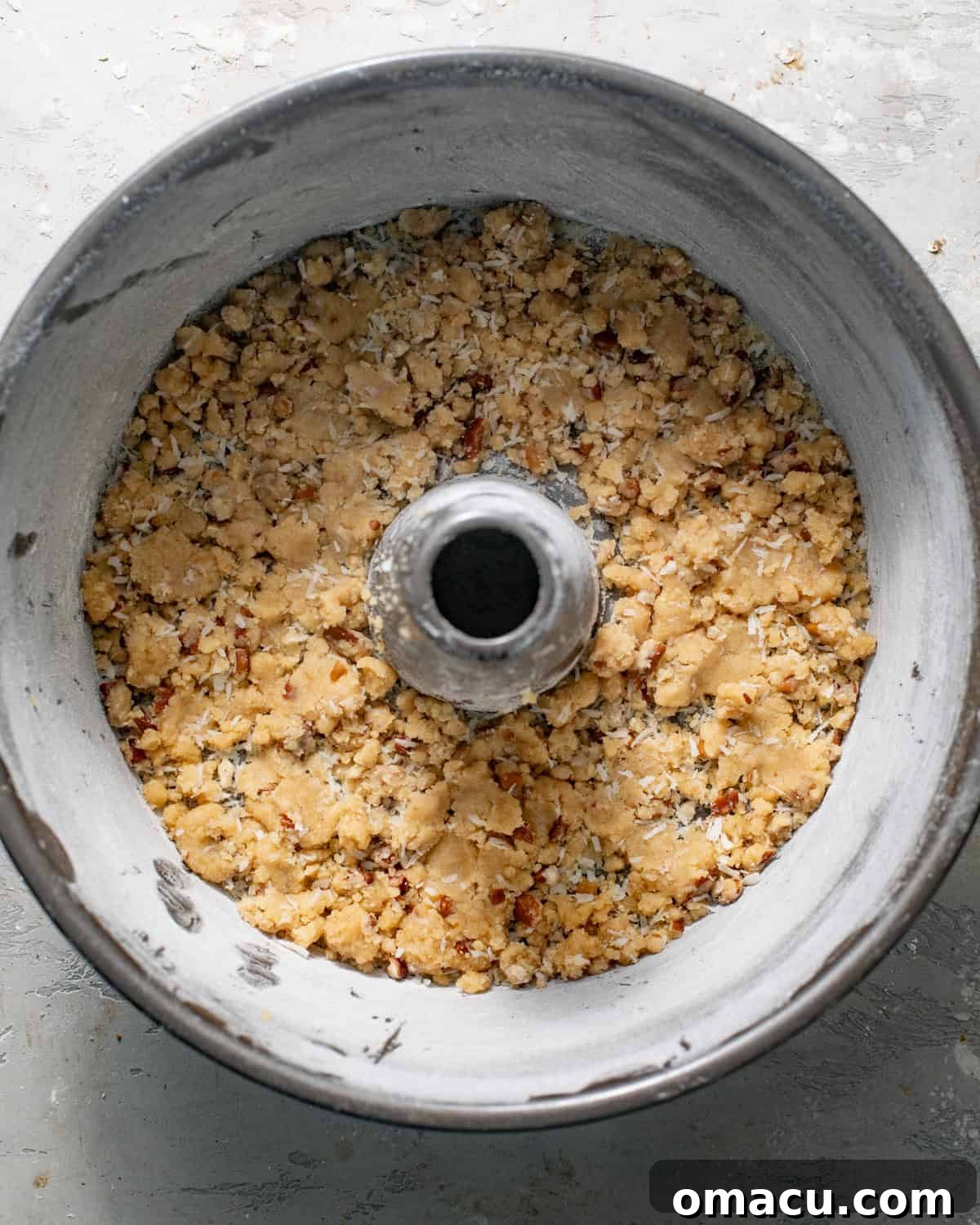 Half of the streusel crunch topping sprinkled evenly on the bottom of a prepared tube pan.