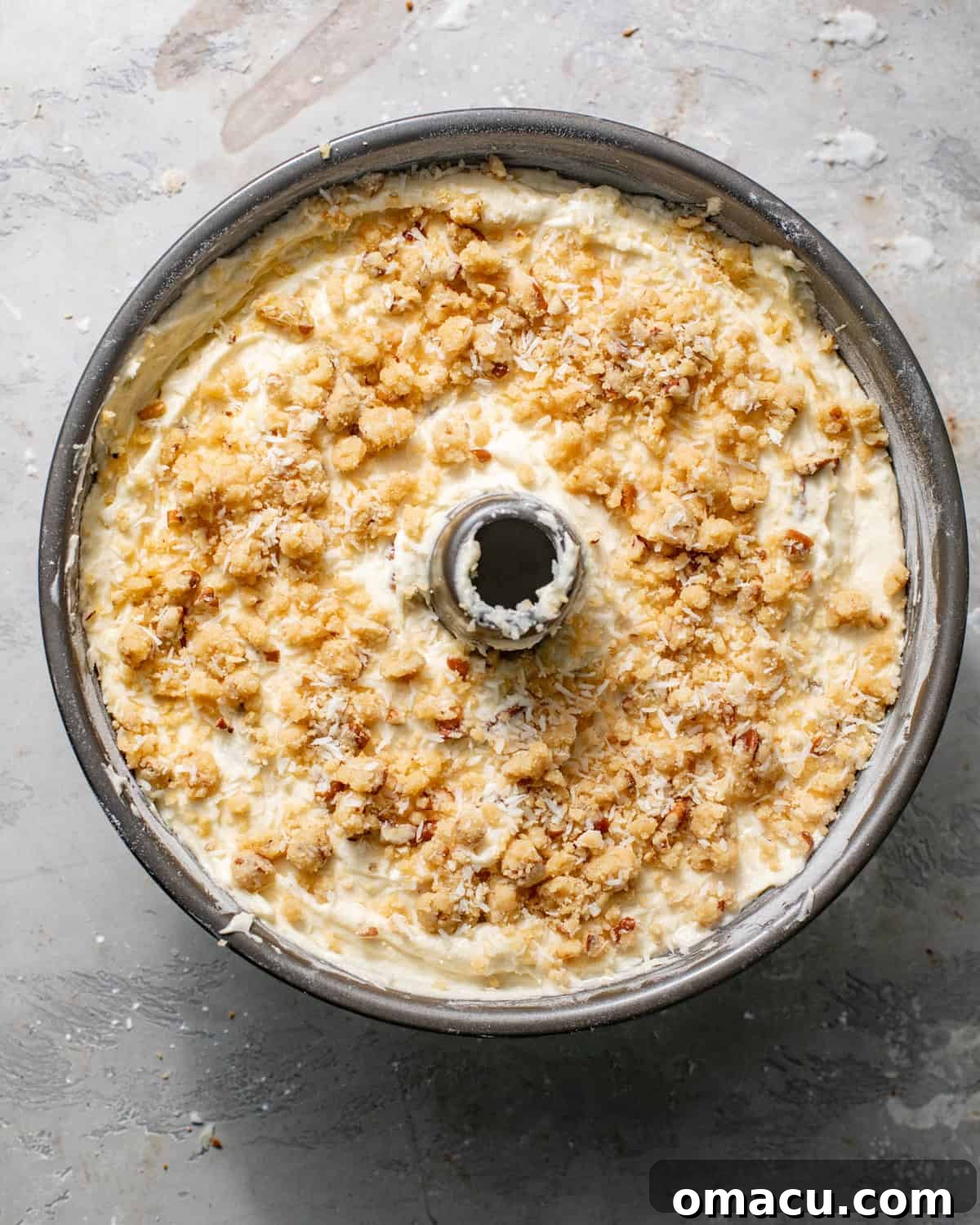 Louisiana crunch cake batter carefully poured over the streusel layer in a tube pan, with remaining streusel on top.