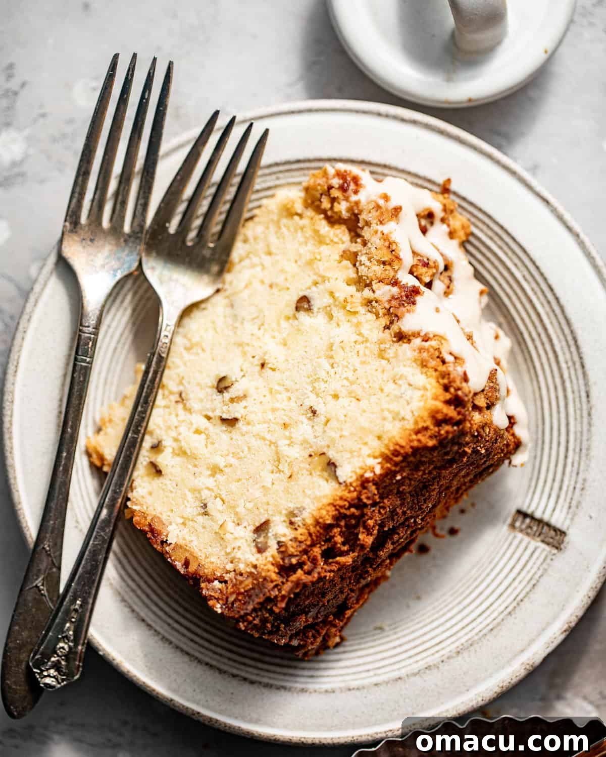 A slice of Louisiana crunch cake on a white plate with a fork, ready to be enjoyed.