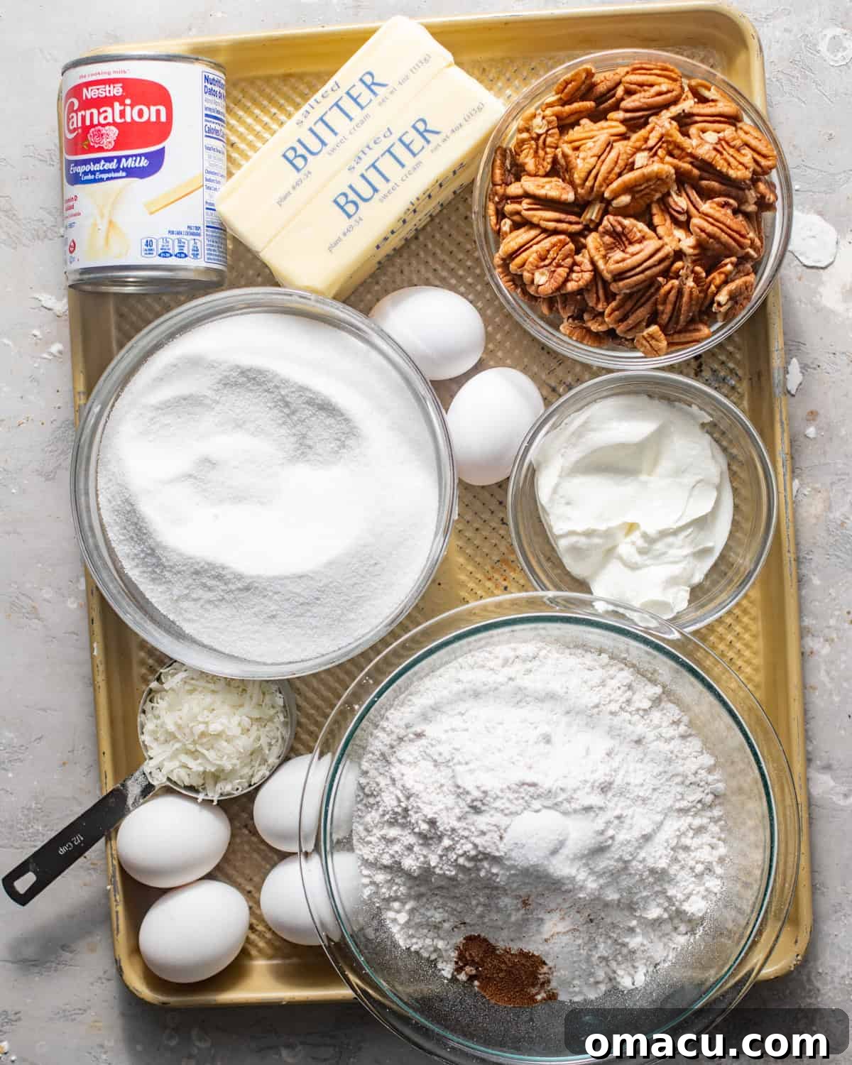 Key ingredients for Louisiana crunch cake laid out on a kitchen counter, including pecans, coconut, flour, and butter.