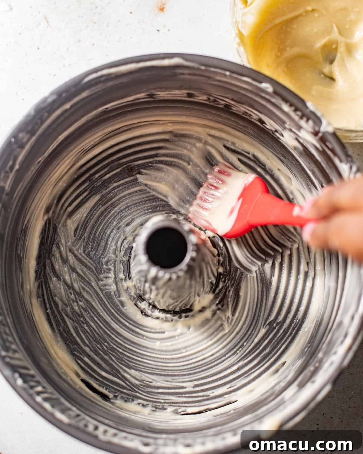 An 18-cup tube pan coated thoroughly with shortening using a pastry brush, preventing sticking.