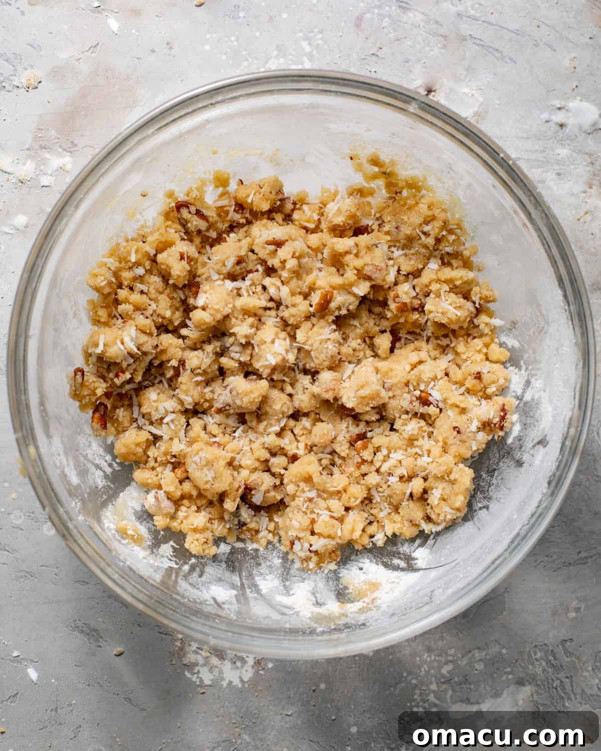Pecan coconut streusel crunch topping being mixed together in a bowl, creating a crumbly texture.