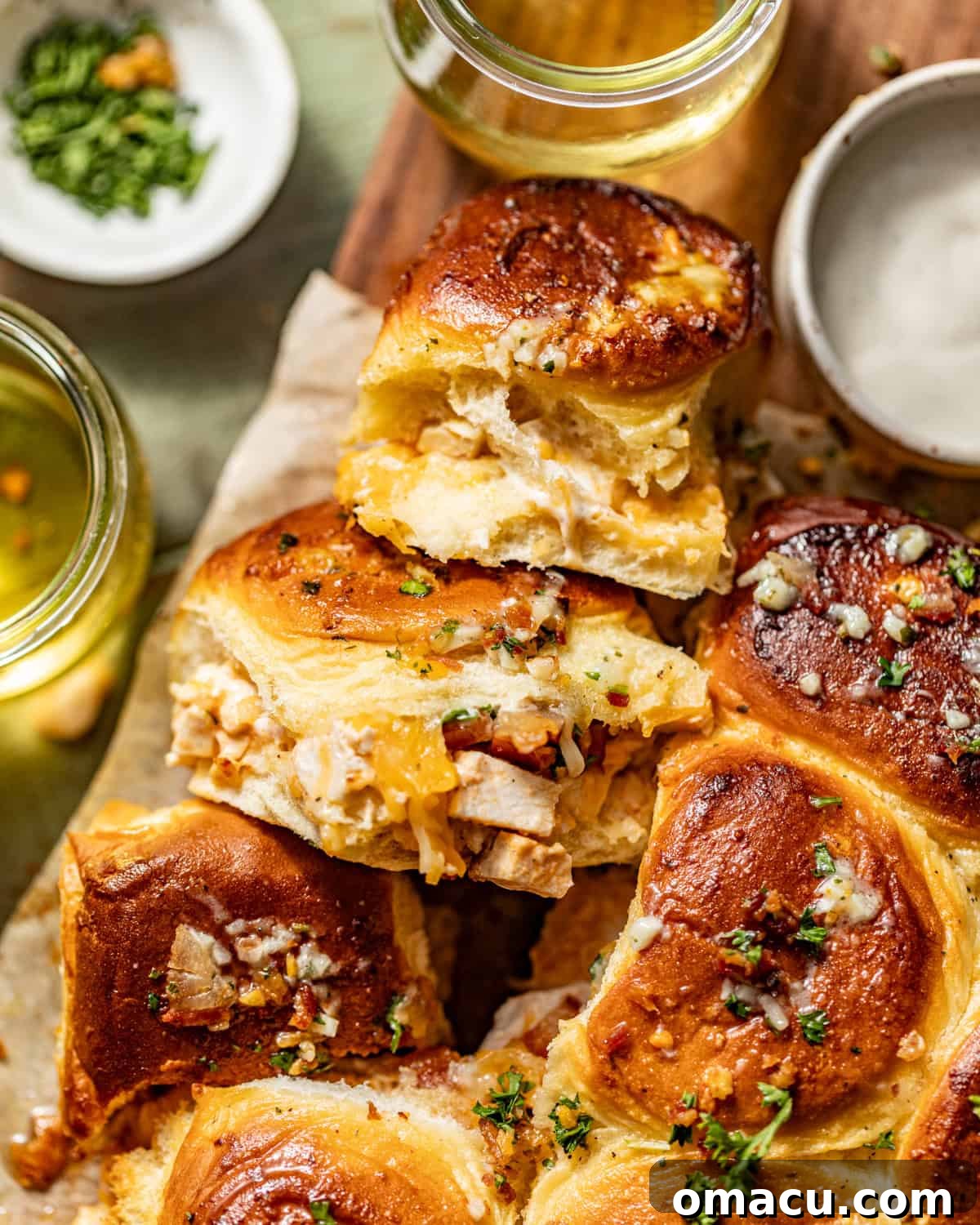 up close chicken bacon ranch sliders on a serving tray next to a bowl of parsley and ranch. 