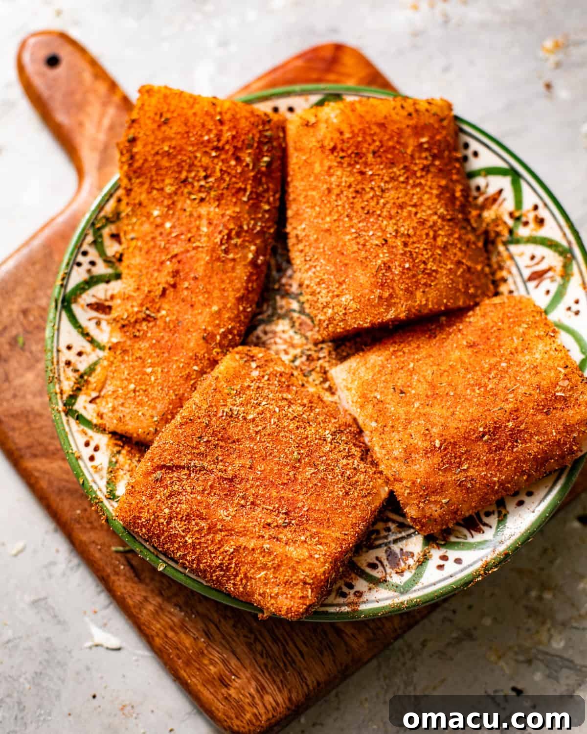 Mahi Mahi fillets arranged on a plate, generously coated with a rich, dark blackening seasoning, ready for pan-searing.