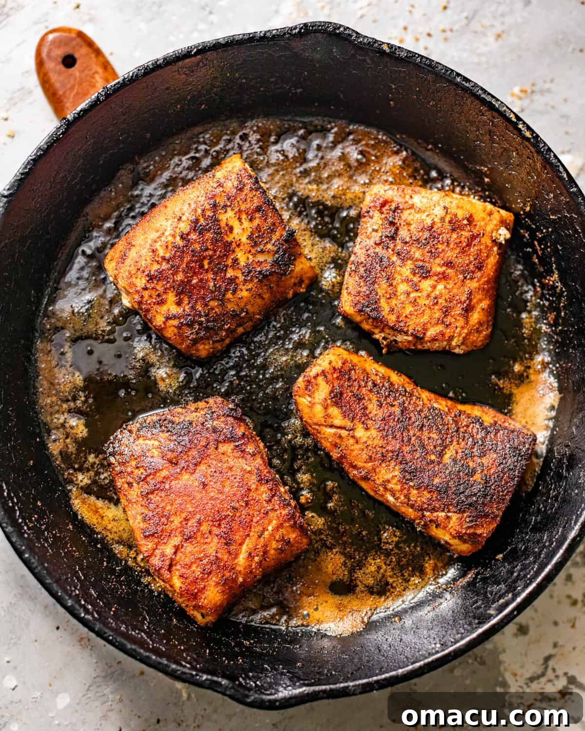 Expertly seasoned Mahi Mahi fillets sizzling intensely in a hot cast iron skillet, developing a dark, crispy blackened crust with visible smoke.