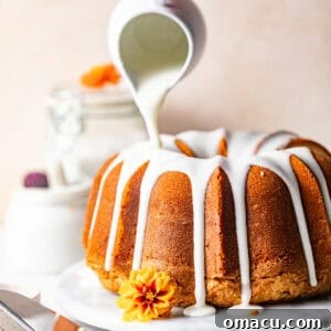 7 flavor pound cake on a cake plate with glaze being poured on top.