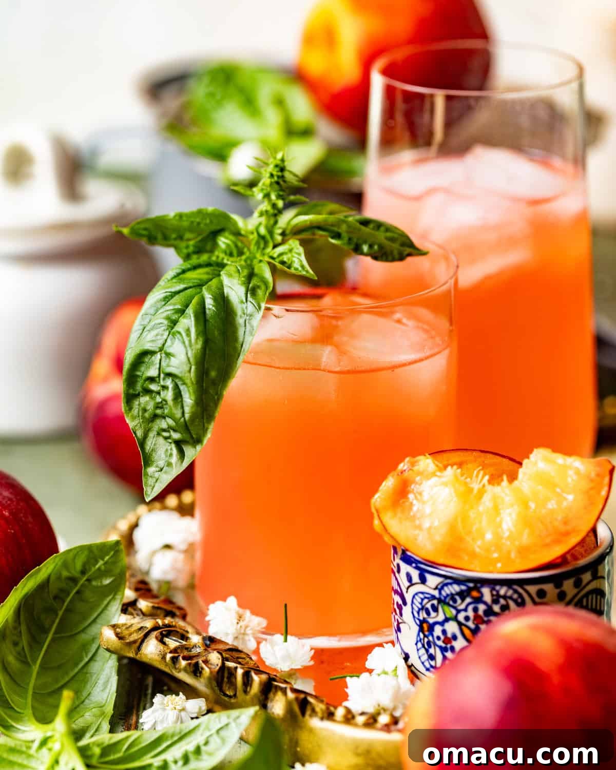 Two glasses of peach lemonade garnished with fresh mint and peach slices, perfect for a summer day.