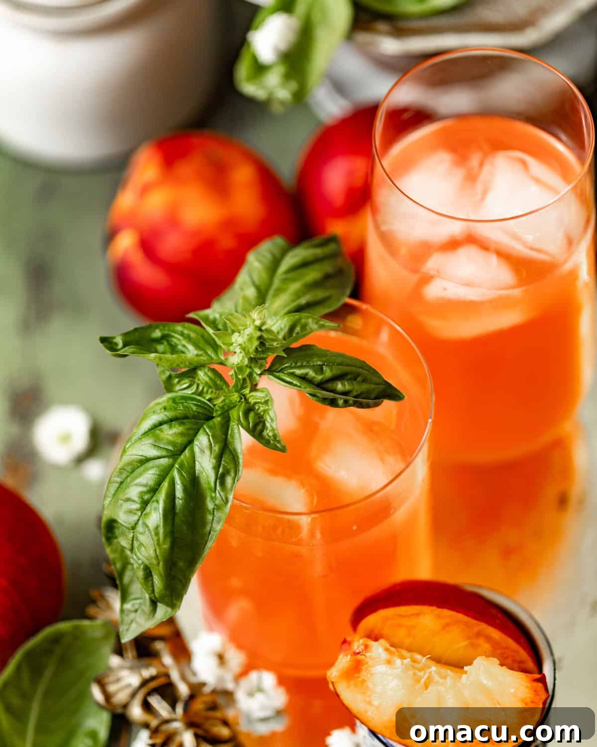 Close-up of peach lemonade in glasses, garnished with fresh basil and mint, ready to be served.