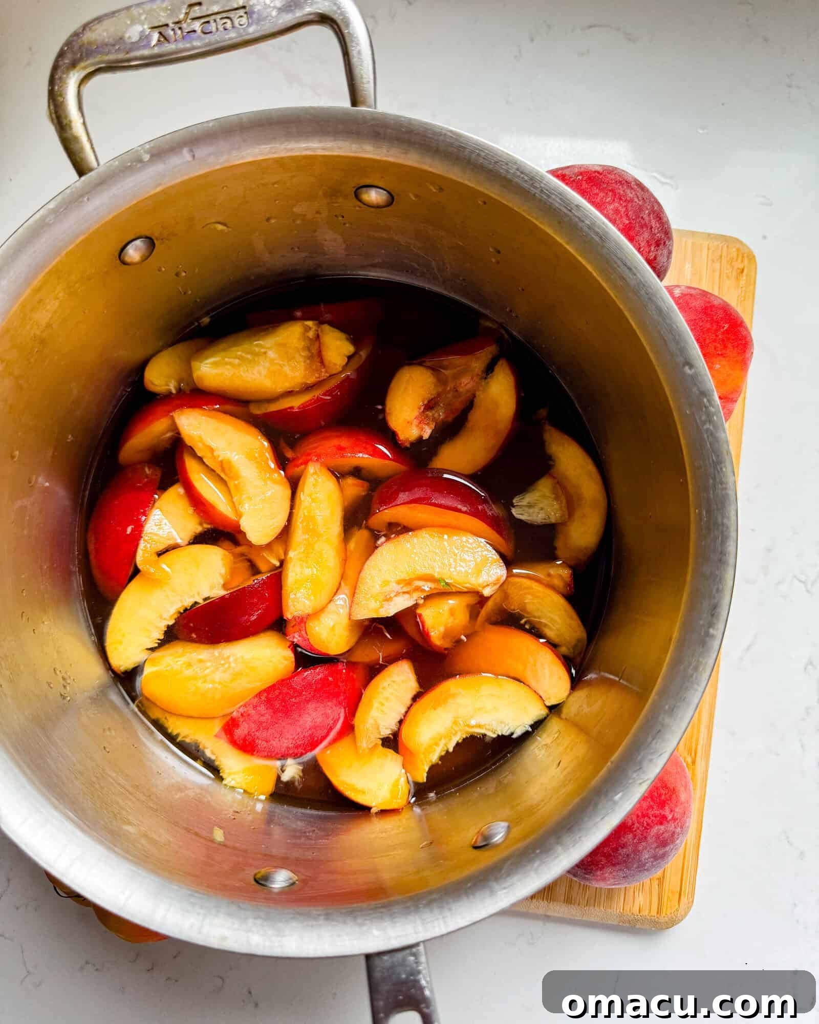 Sliced peaches simmering in a saucepan with brown sugar and water, forming the peach simple syrup.