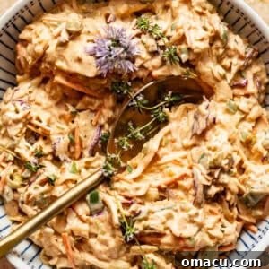Cajun coleslaw in a bowl with a spoon, ready to be served.