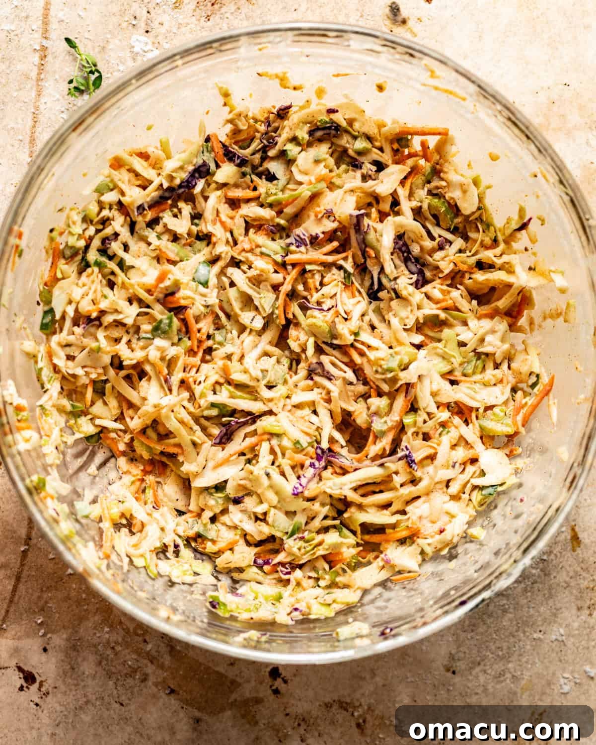 Cajun coleslaw ingredients, including shredded cabbage and diced vegetables, tossed together with the creamy dressing in a large bowl.