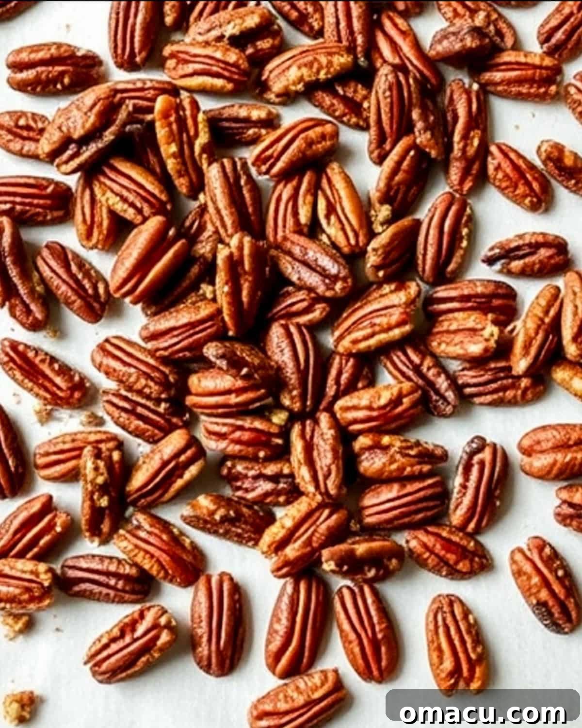 Toasted pecans evenly spread on a baking sheet, golden brown and fragrant.