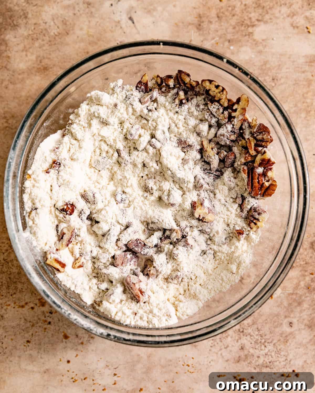 Dry ingredients for the prune cake batter, including flour, chopped pecans, and spices, mixed in a bowl.