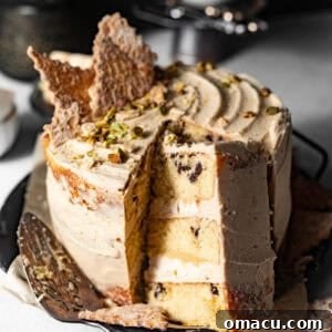 A beautifully sliced cannoli cake on a cake plate, garnished with crushed cannoli shells, ready to be served.