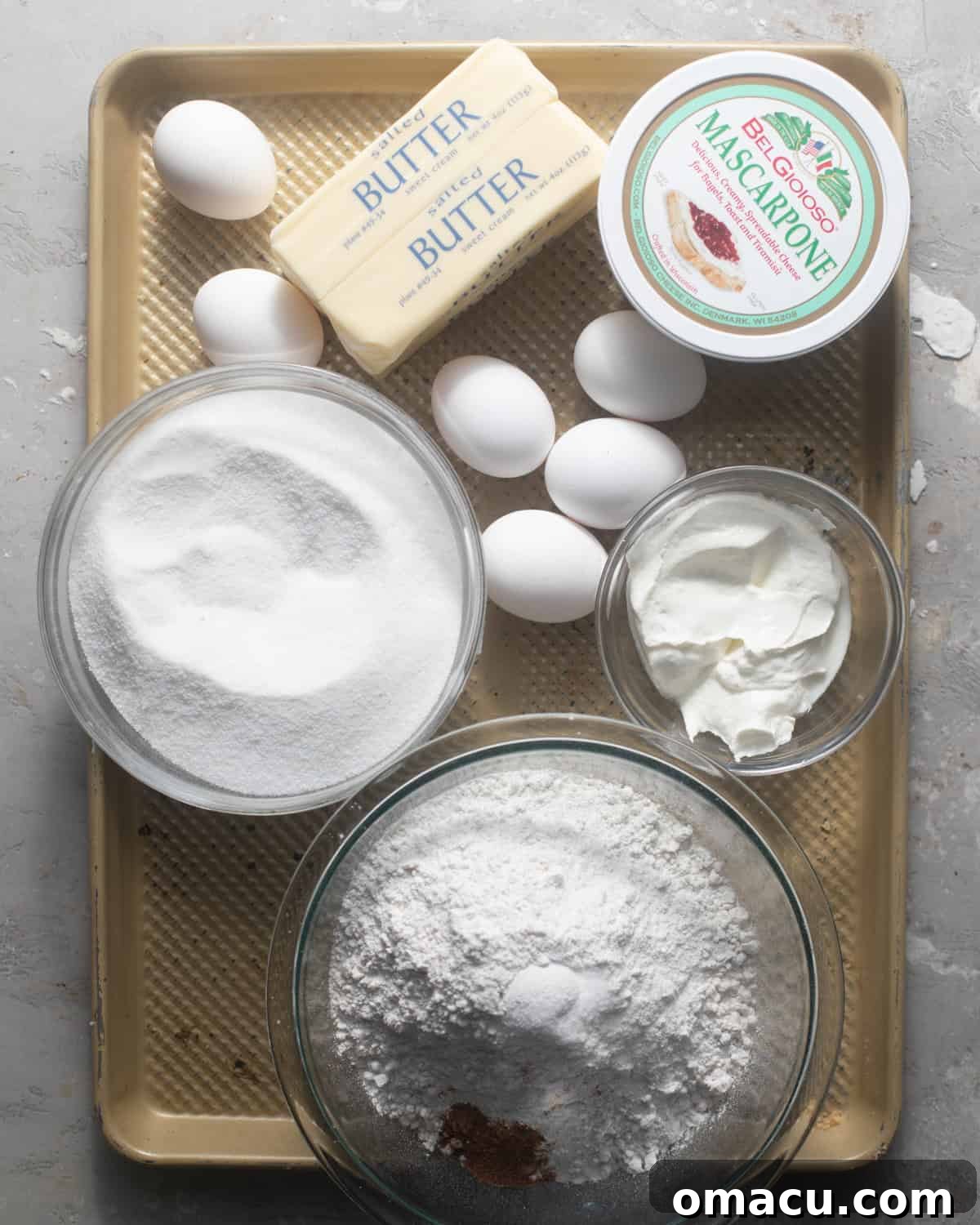 A collection of fresh, high-quality ingredients laid out on a baking sheet, ready for making cannoli cake.