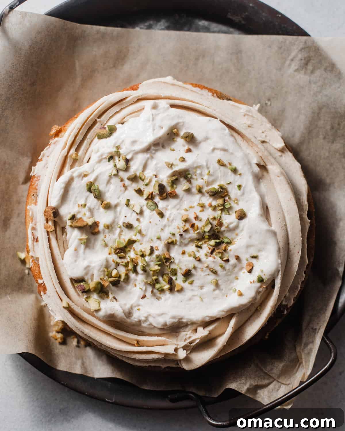 A layered cannoli cake with a thin layer of buttercream, a generous ricotta filling, and chopped pistachios on top.