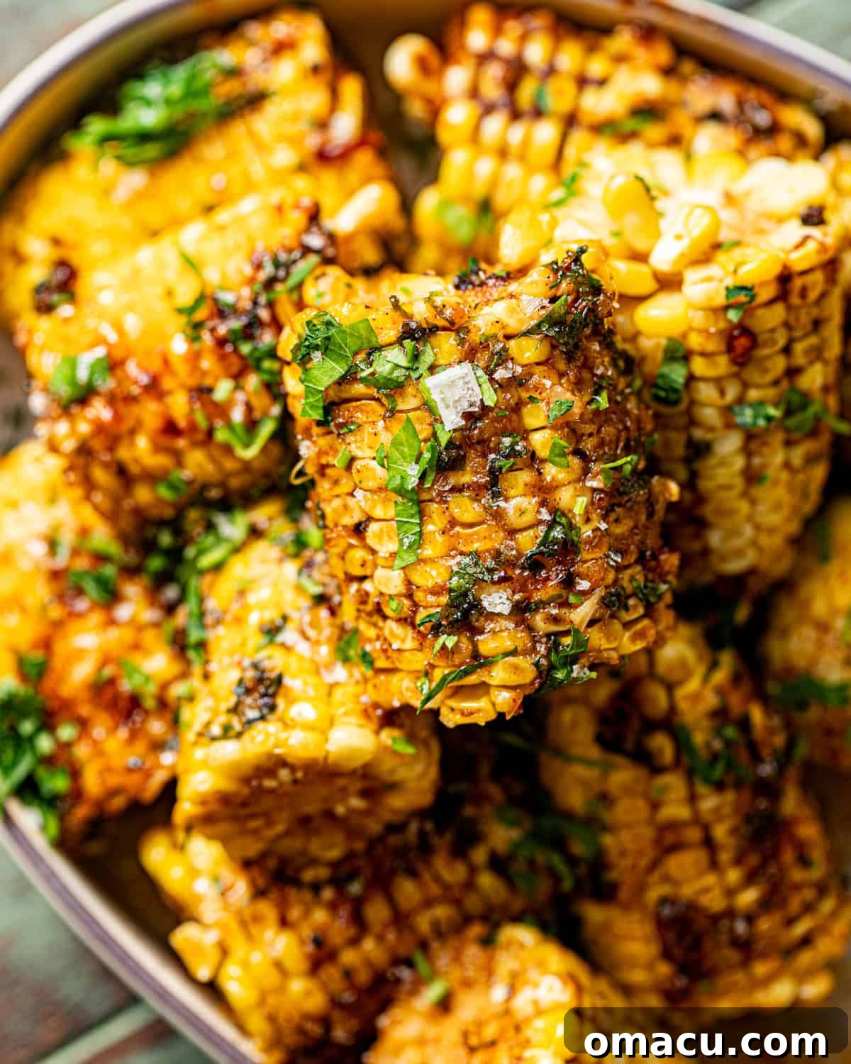 Overhead shot of Cajun corn on the cob in a serving bowl with fresh parsley.