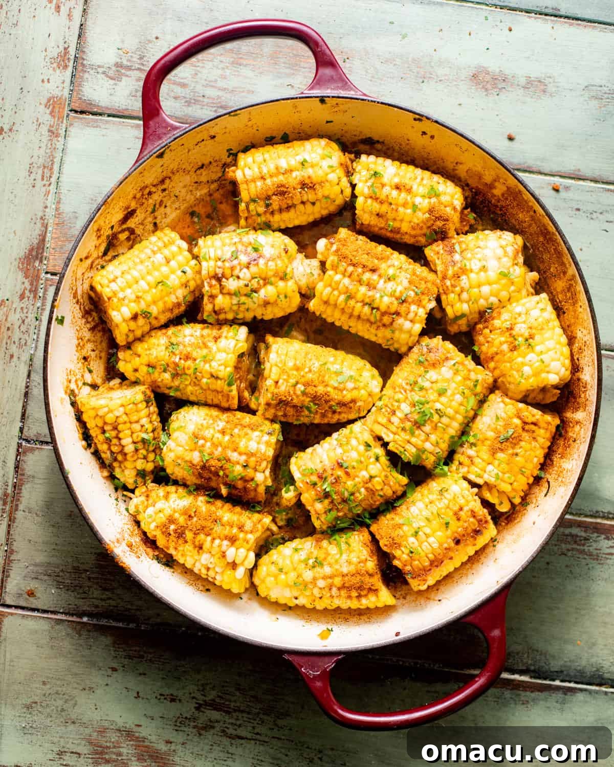 Seasoned corn on the cob in a pot, coated in aromatic garlic butter.