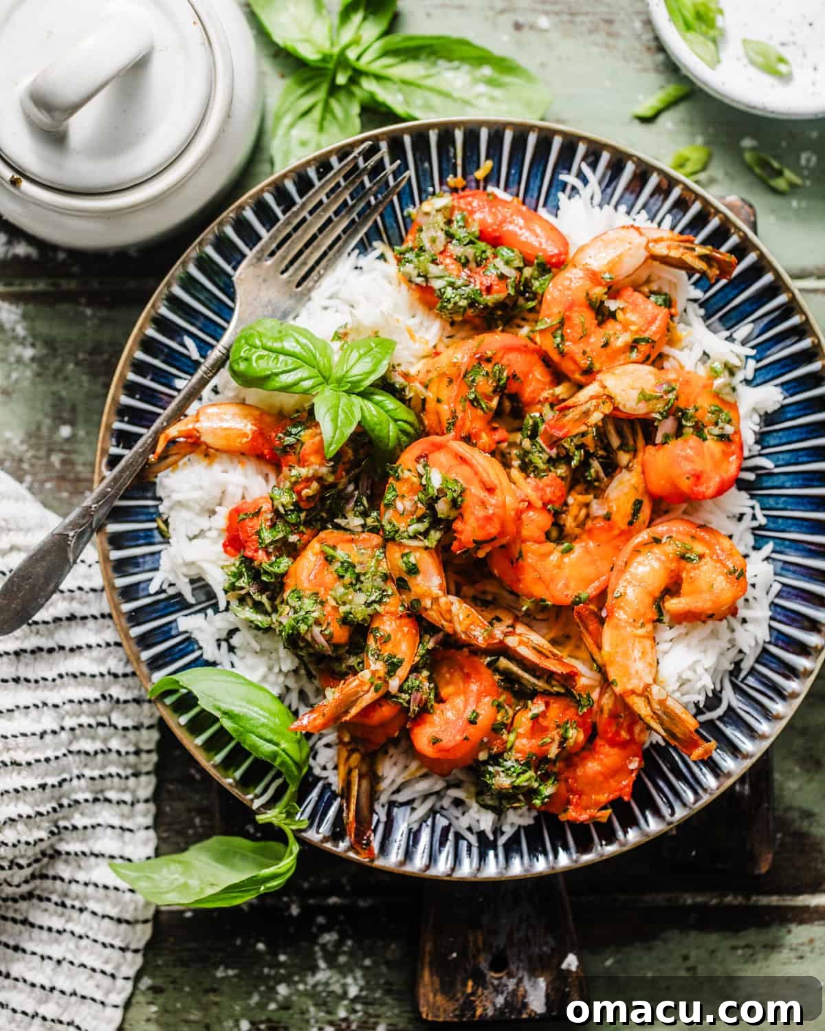 A vibrant plate of shrimp chimichurri served over fluffy white rice, generously topped with fresh basil, showcasing the rich colors of the dish.
