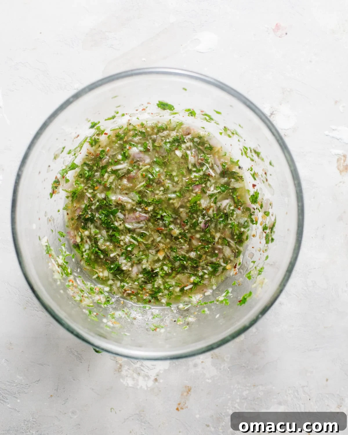 The freshly prepared chimichurri sauce, a bright green mixture with visible herb flecks, resting in a bowl, ready to be used.