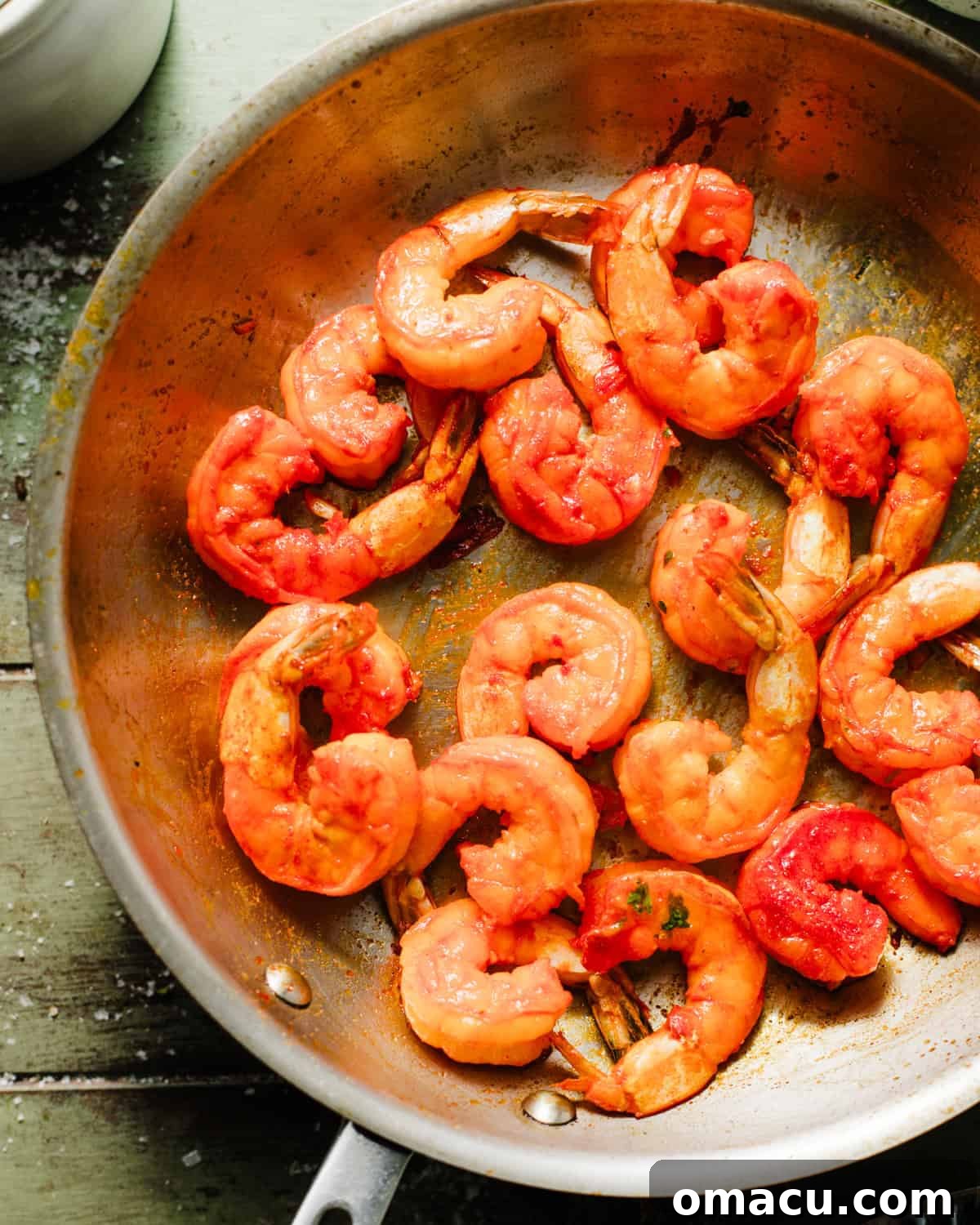 Perfectly cooked, pink, and slightly curled shrimp sizzling in a cast iron skillet, hinting at a delicious sear.