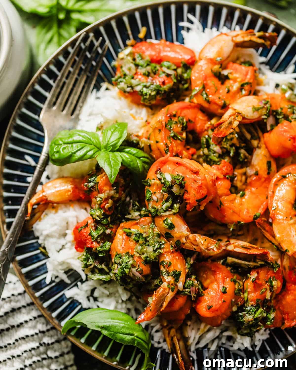 A close-up, mouth-watering shot of shrimp chimichurri served on a plate, nestled on a bed of rice, with a fork poised to scoop up a delicious bite.