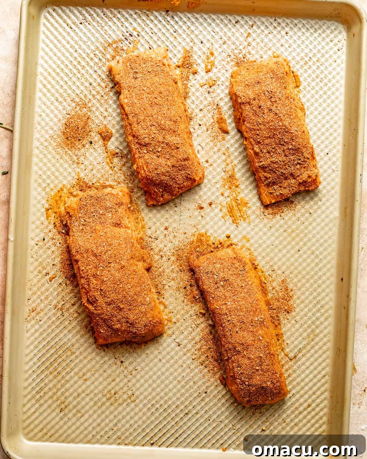 salmon fillets on a baking sheet with melted butter mixture brushed on top. 