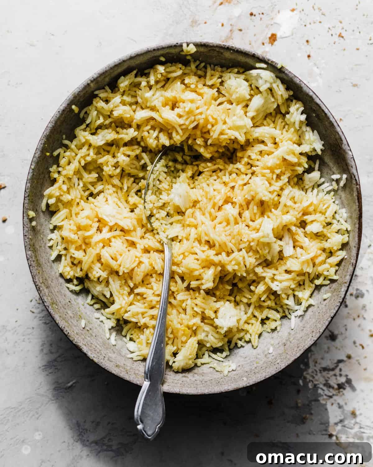 Fluffy seasoned rice in a bowl, enriched with flavorful gravy from the baked Mediterranean chicken, ready for assembly.