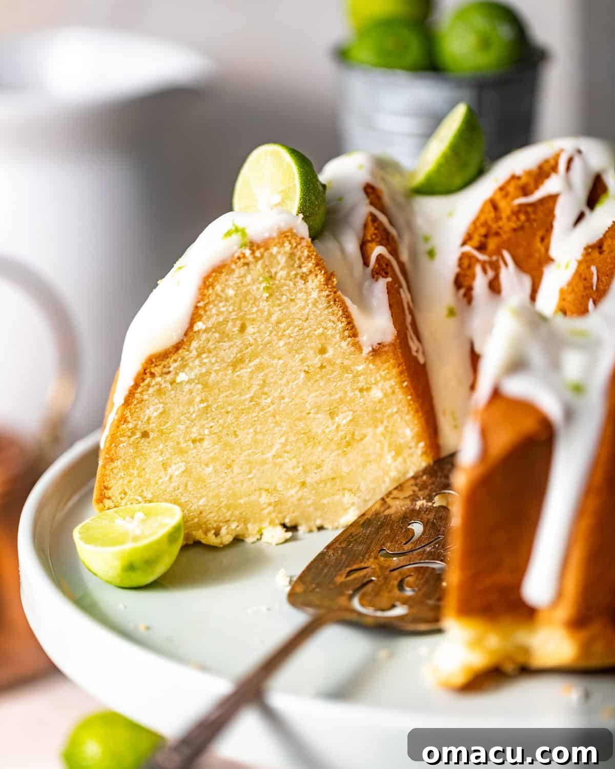 Key lime pound cake sliced on a cake stand with a cake knife.