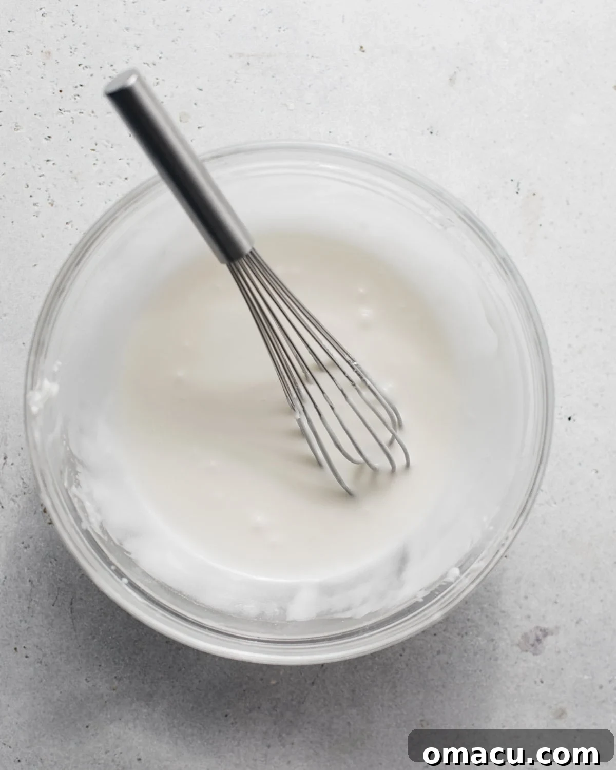 Key lime glaze in a bowl with a whisk.