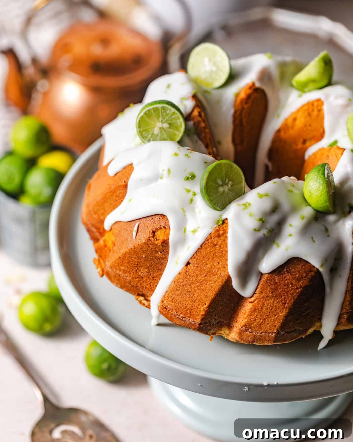Overhead photo of key lime pound cake on a cake stand with fresh key limes.