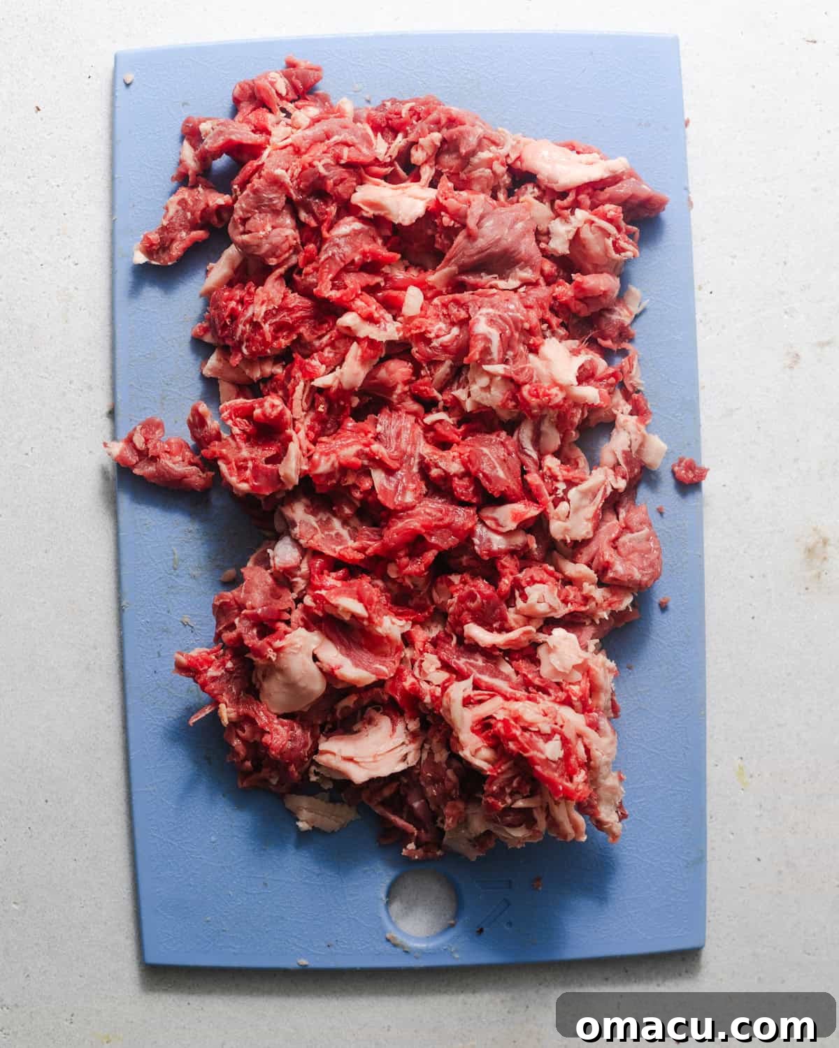 Thinly sliced ribeye steak that has been coarsely chopped into smaller bits, ready for cooking.