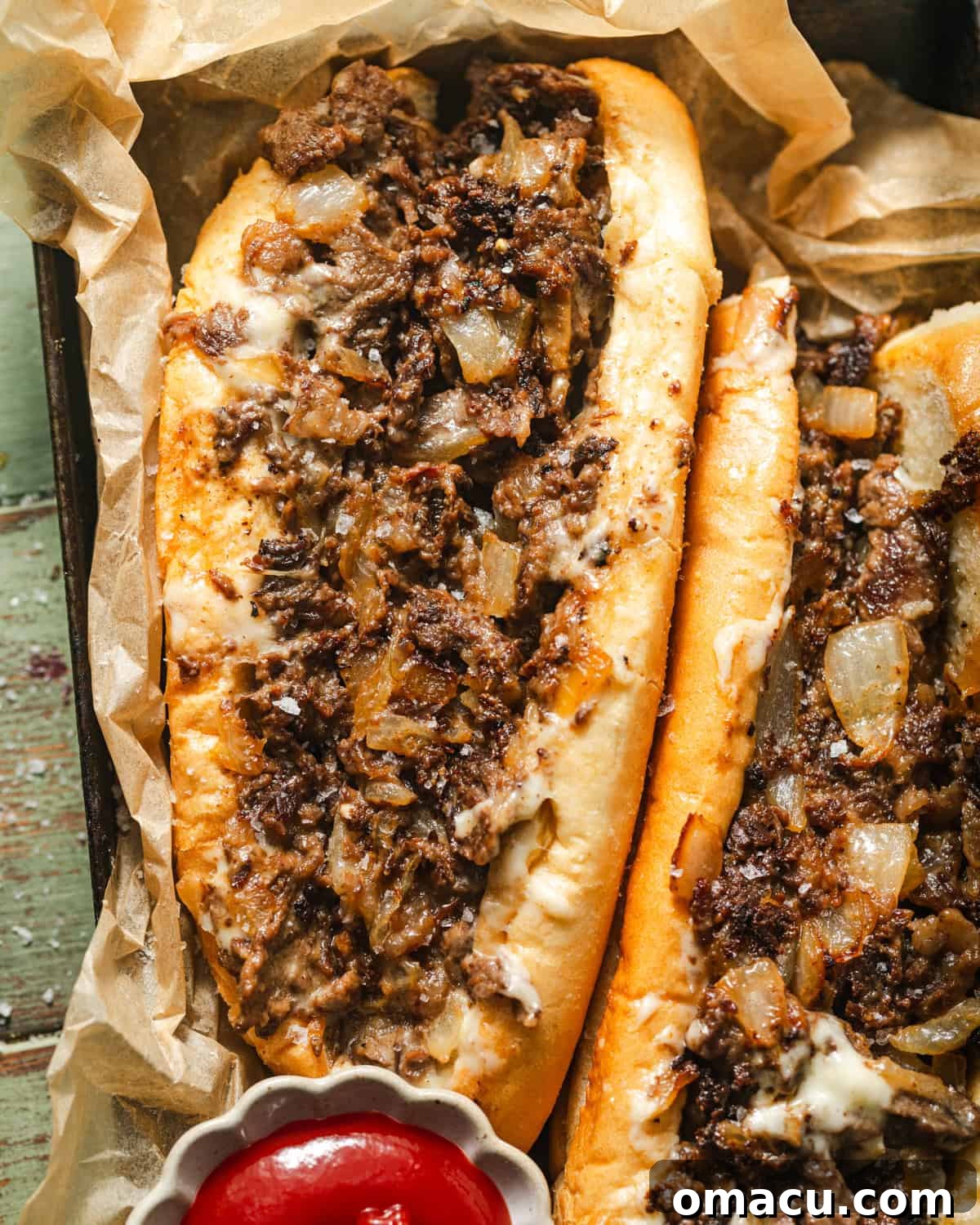 A close-up photograph of two incredibly delicious Philly cheesesteaks, showcasing the melted cheese and tender steak, served on a plate.