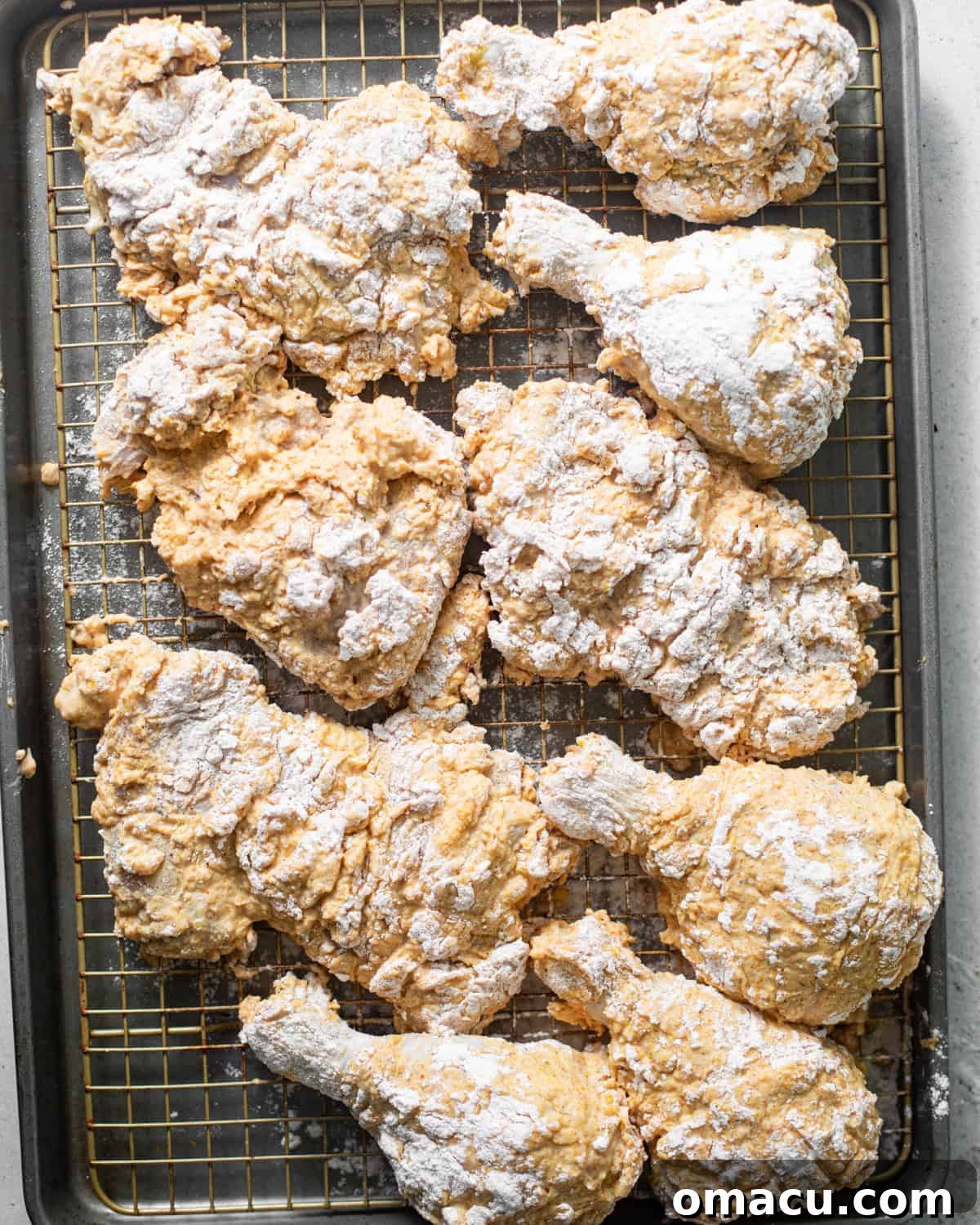 Bredded chicken pieces resting on a wire rack, showing off their craggy, well-coated texture, awaiting frying.