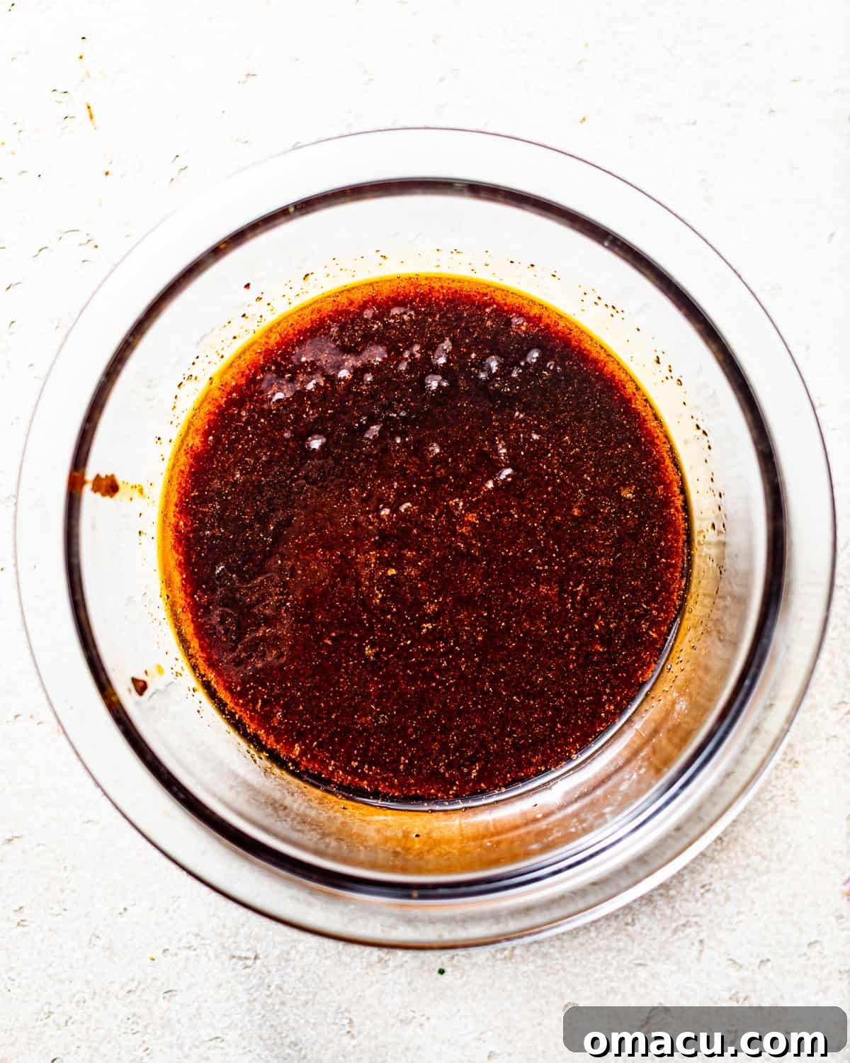 A rich, red Nashville Hot Chicken sauce simmering in a bowl, its glossy texture indicating a perfect blend of spices and oils.