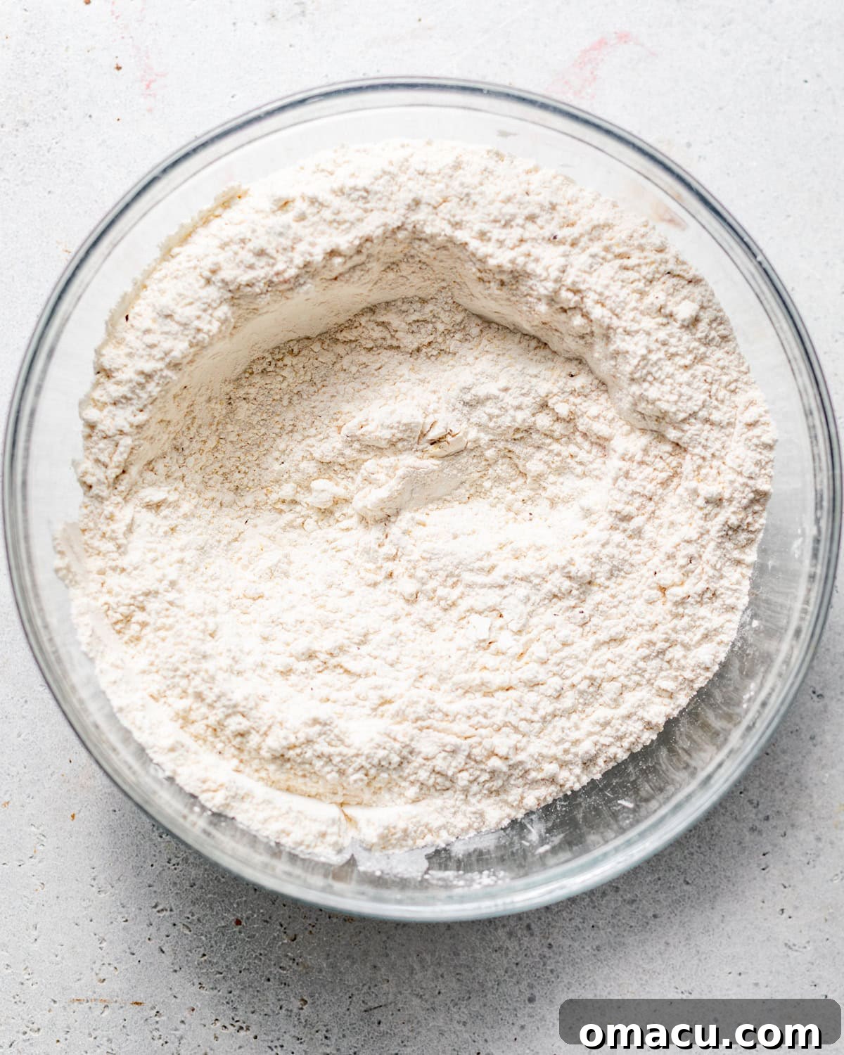 A close-up shot of a large mixing bowl containing the perfectly whisked flour dredge, a light, seasoned blend of all-purpose flour, cornstarch, sazon, and lemon pepper seasoning.