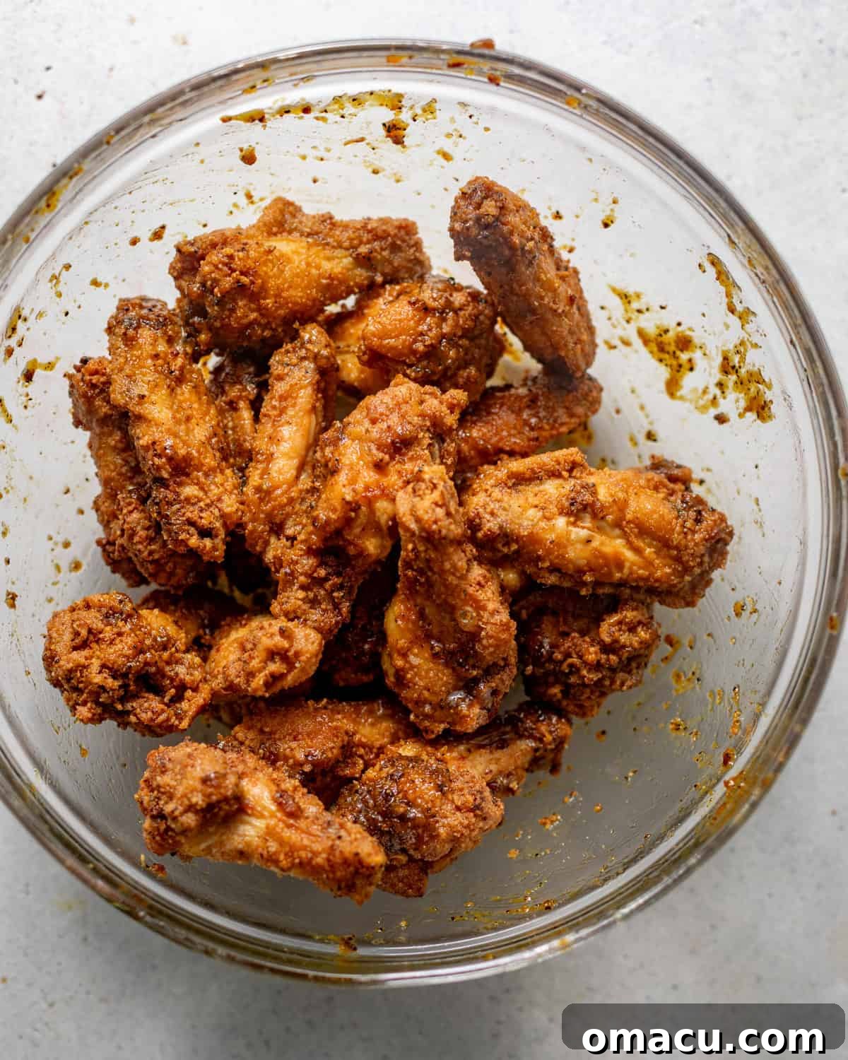 A large bowl filled with golden-brown fried chicken wings, generously coated and glistening with the vibrant lemon pepper butter sauce, ready to be served.