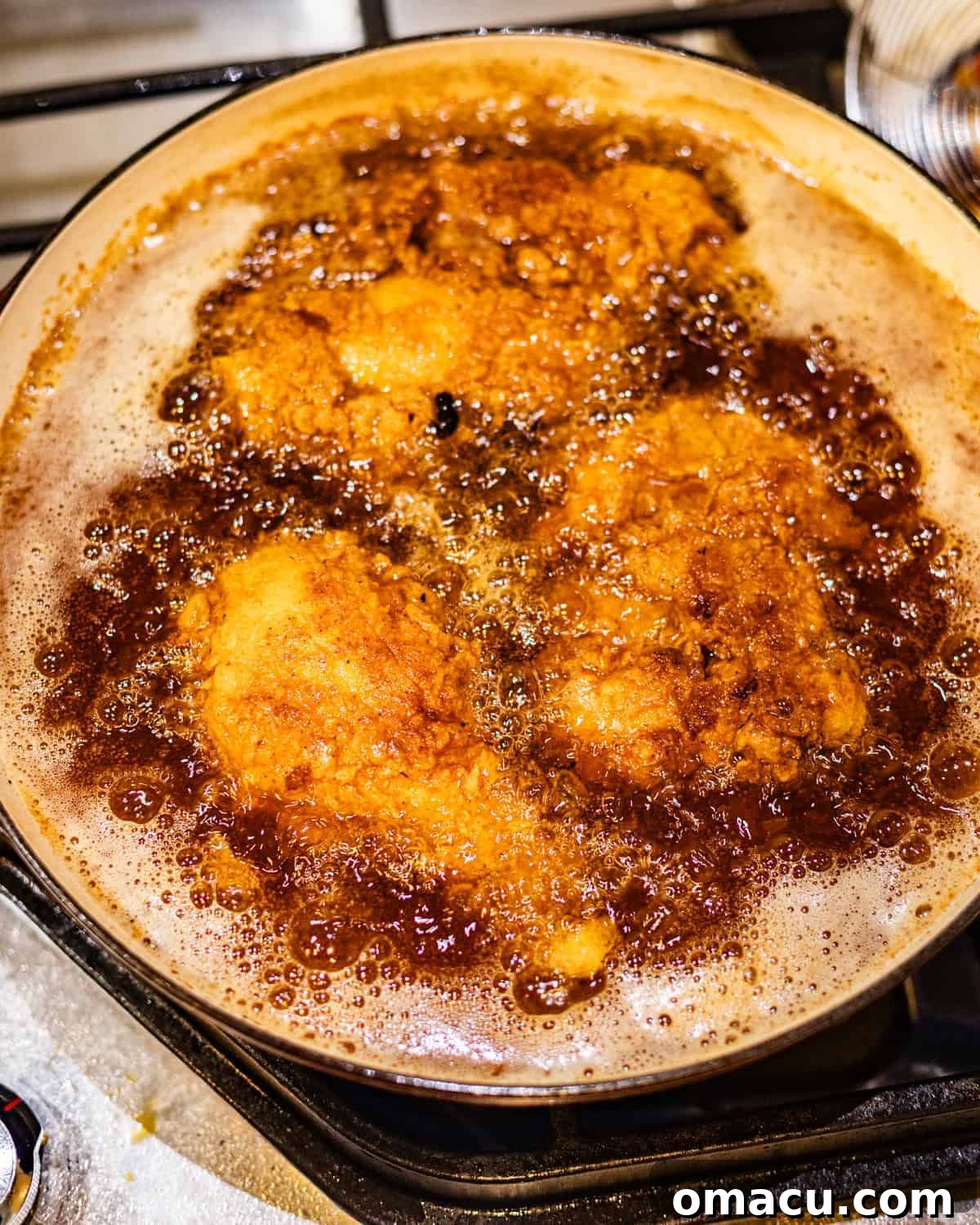 chicken frying in hot oil in a pot.