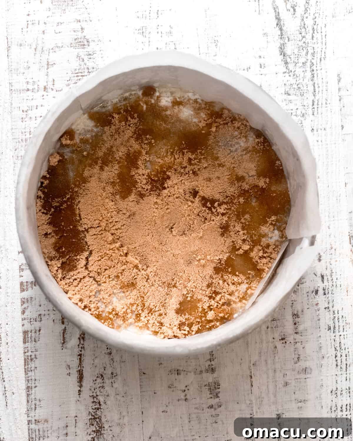 Melted butter evenly spread across the bottom of the cake pan, topped with a generous sprinkle of brown sugar.