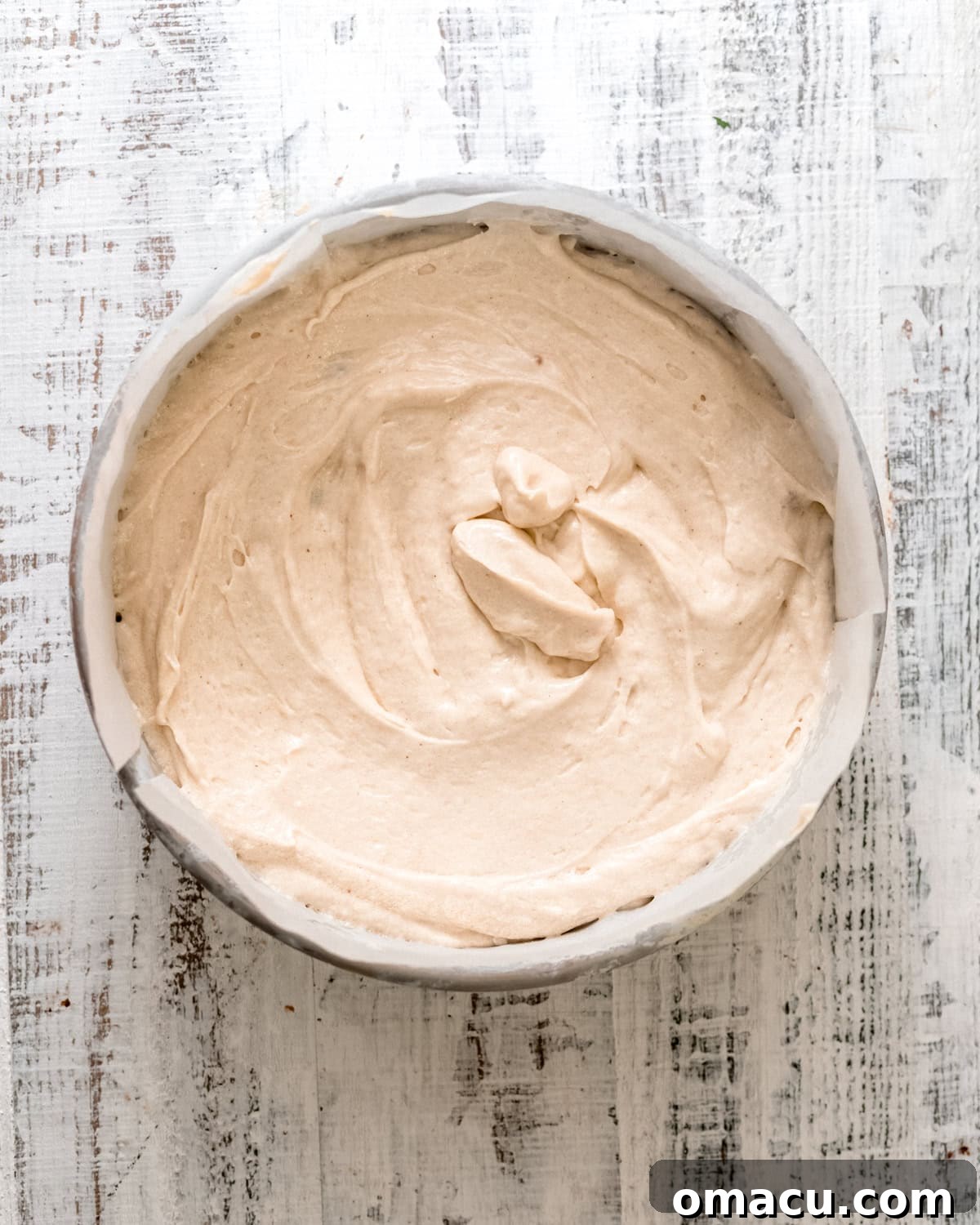 Smooth cake batter gently poured over the blueberry layer, filling the cake pan evenly.