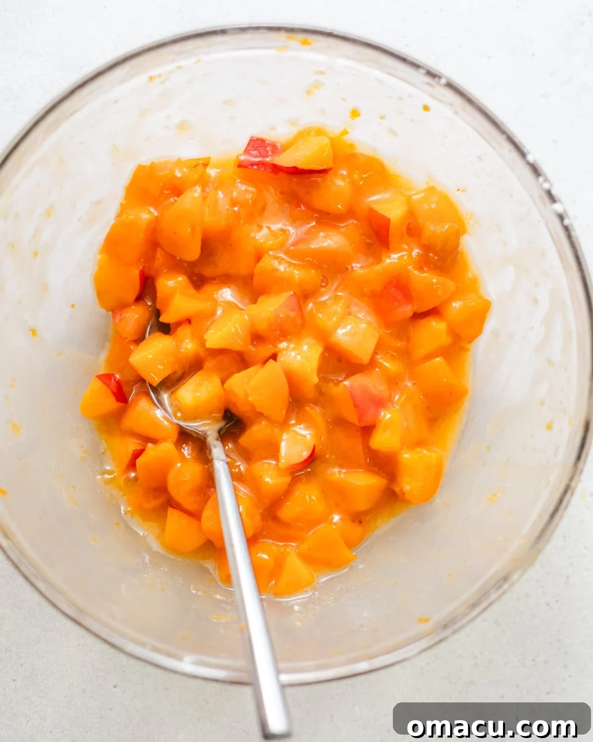 Chopped fresh apricots mixed with cornstarch and apricot jam in a bowl, preparing the juicy filling for the cake. This step highlights the fresh ingredients for the fruit swirl.