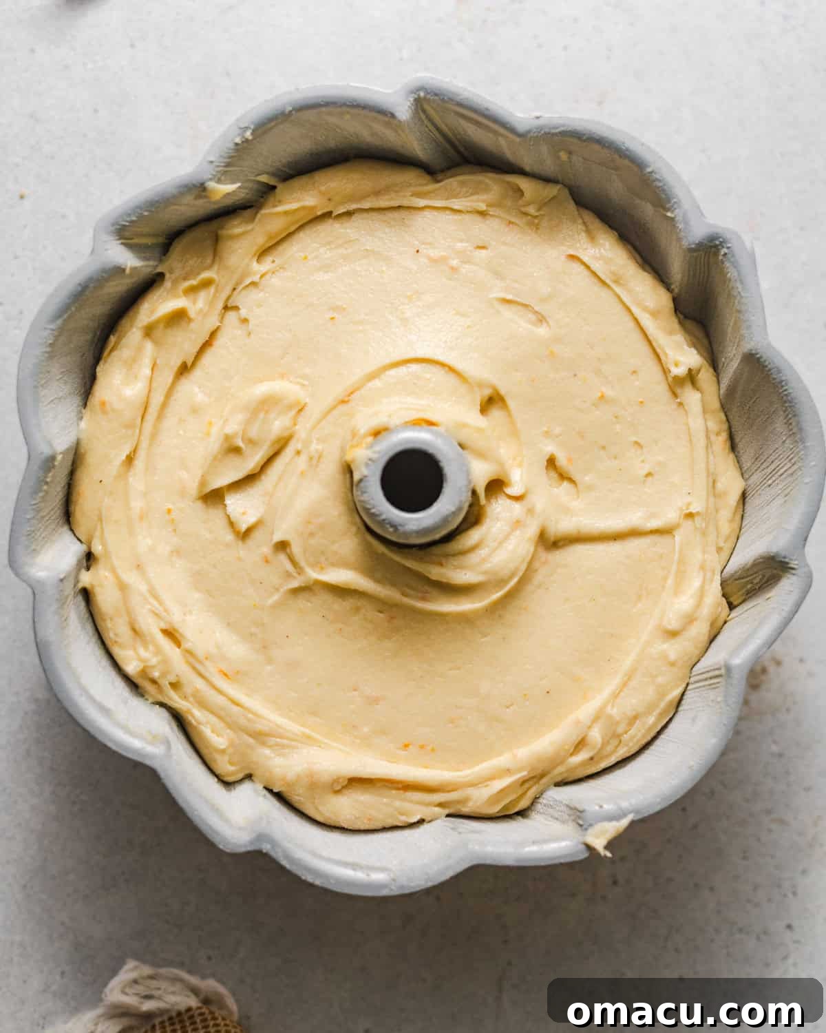 The first half of the apricot cake batter smoothly poured into a thoroughly prepared bundt pan, forming the base layer for the fruit filling.