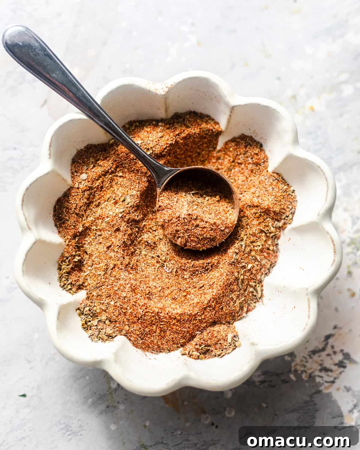 Homemade Cajun seasoning in a small bowl with a spoon, ready to be used.