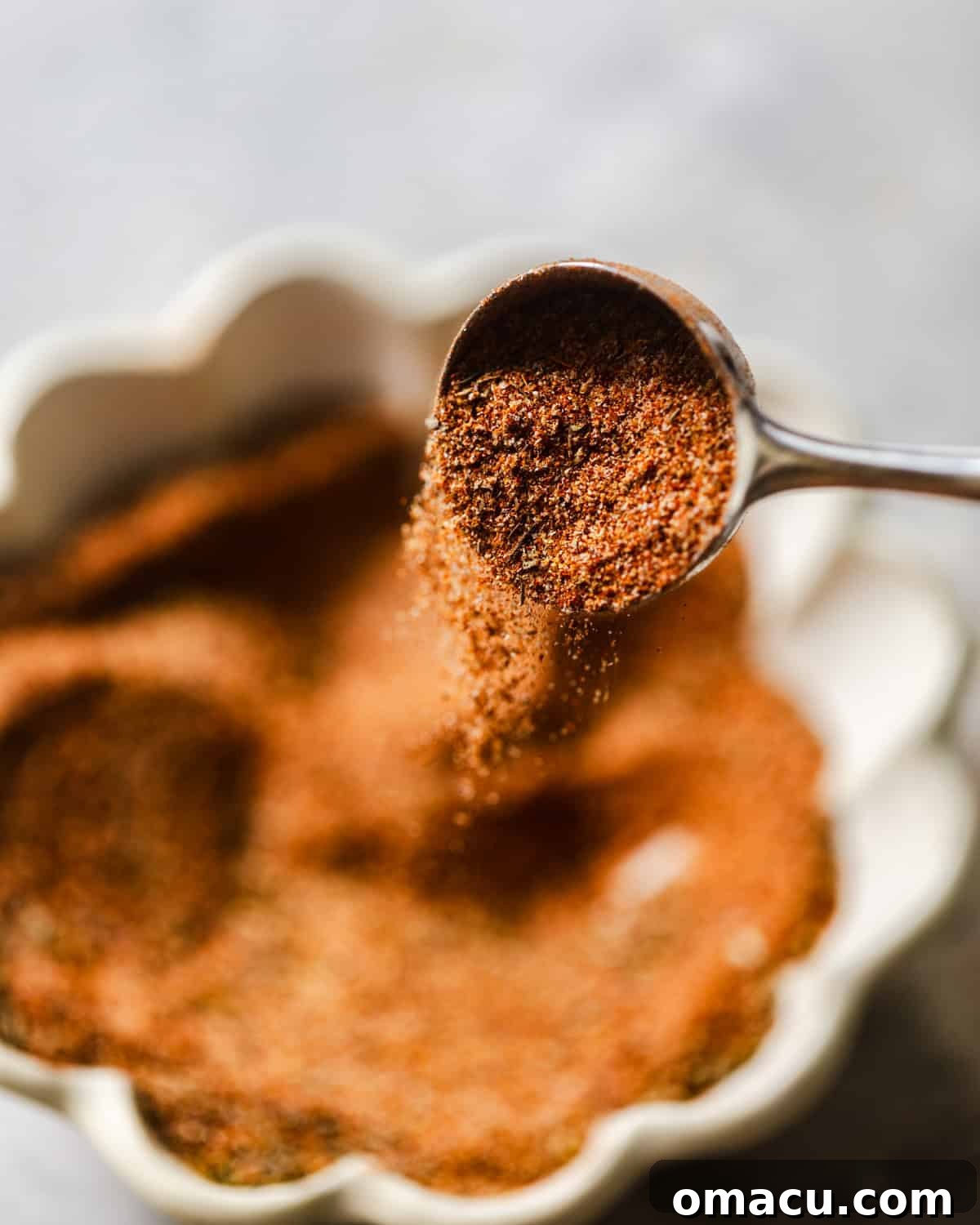 Close-up photo of homemade Cajun seasoning on a spoon, illustrating its rich color and texture.