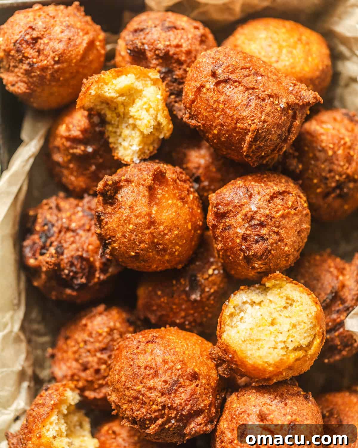 Close-up overhead view of golden hush puppies in a parchment-lined basket, ready to serve.