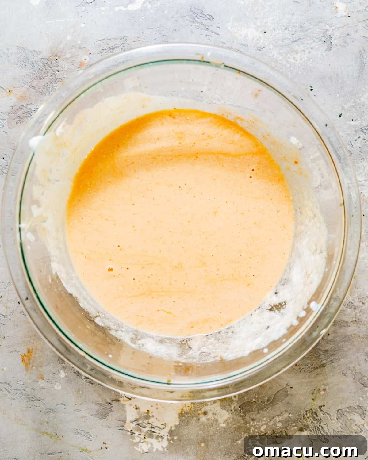 A separate bowl holding the smoothly whisked wet batter mixture, essential for adhesion and flavor.