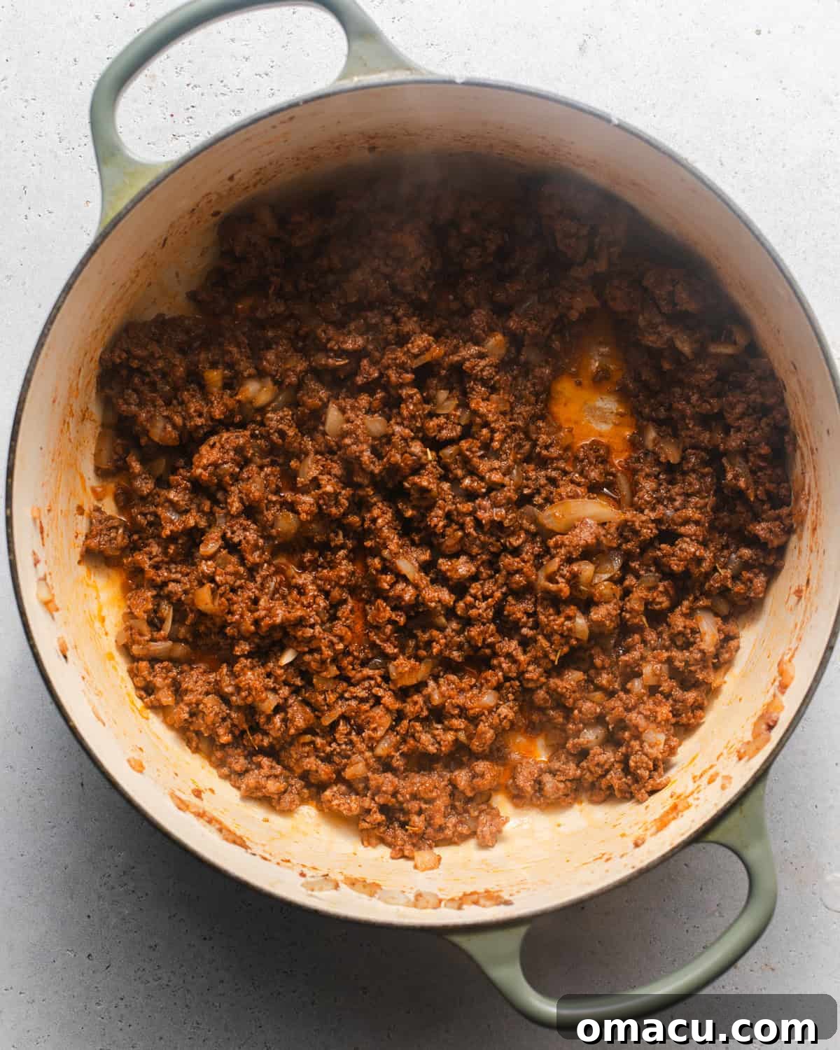 Ground beef and diced onions cooking in a large pot until browned.