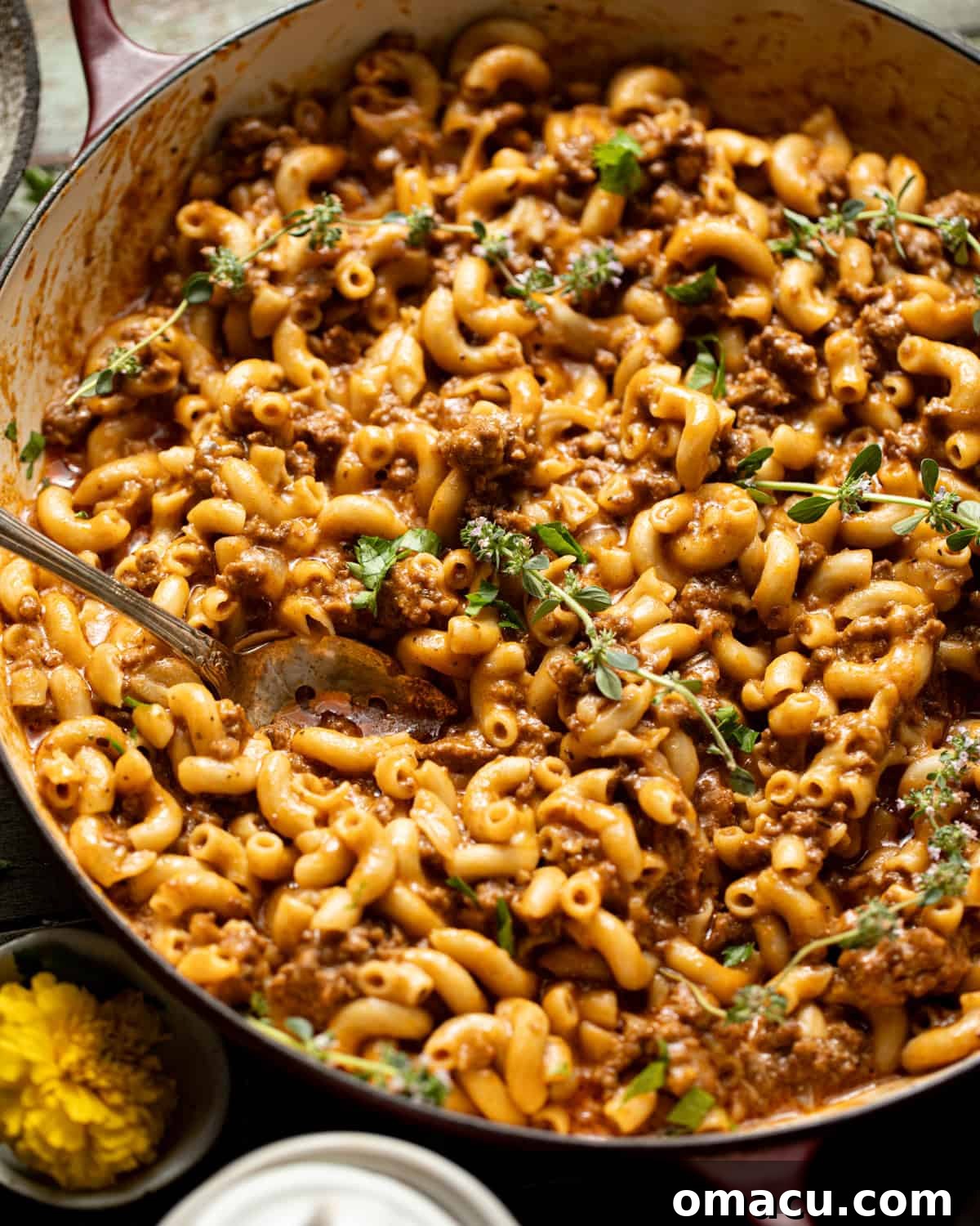 Finished homemade Hamburger Helper in a pot, garnished with fresh herbs, with melted cheese.